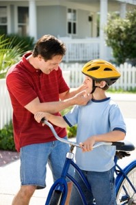 Dad helping son with bike helmet.