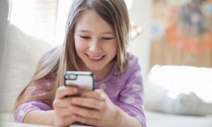 Young girl text messaging with mobile phone on sofa